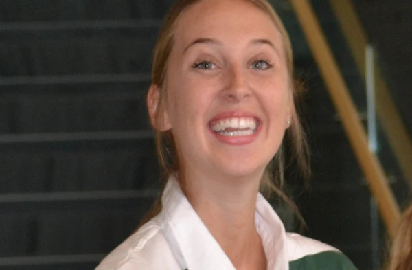 A closeup headshot of a smiling woman with her hair pulled back.